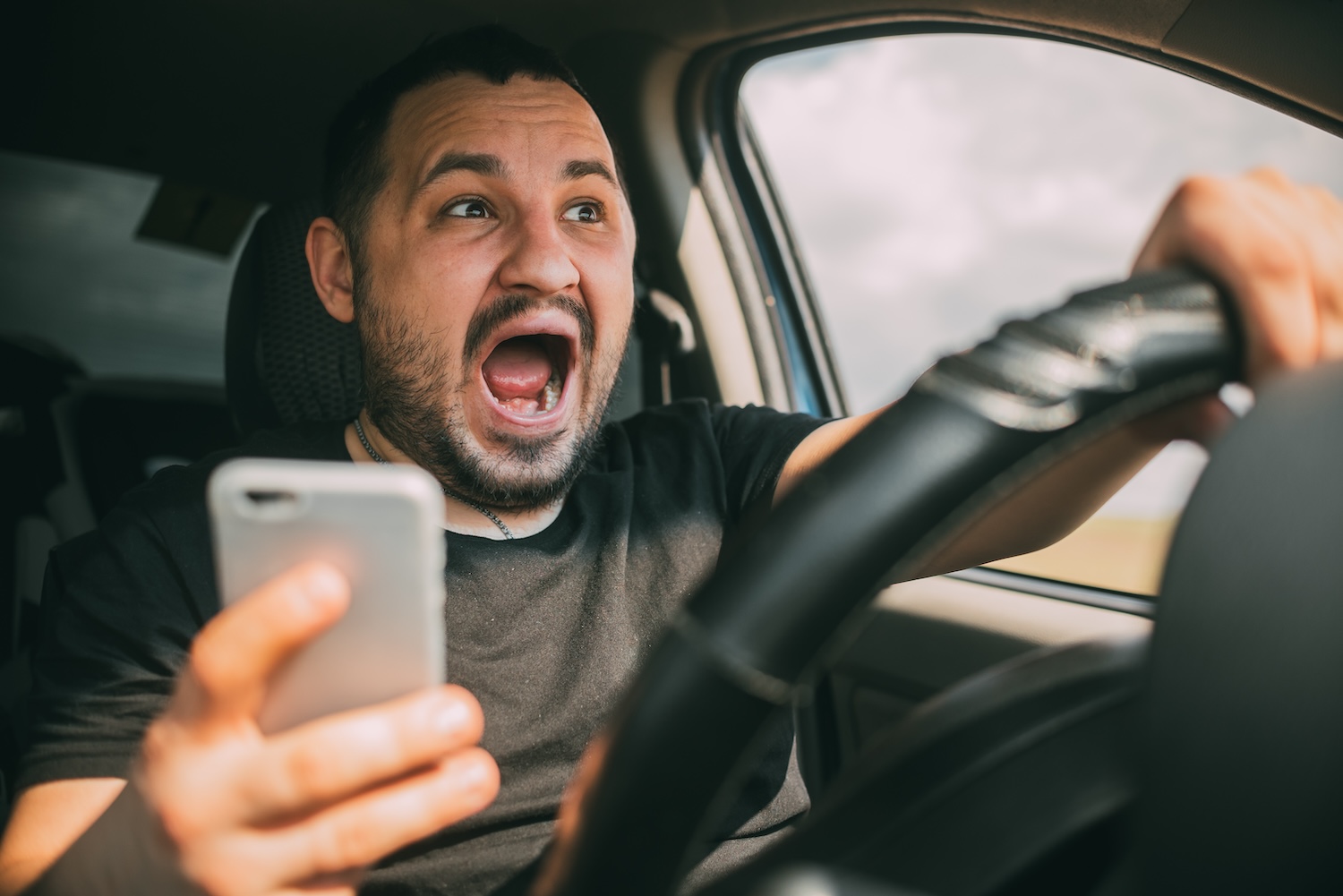 Person texting and driving with look of panic