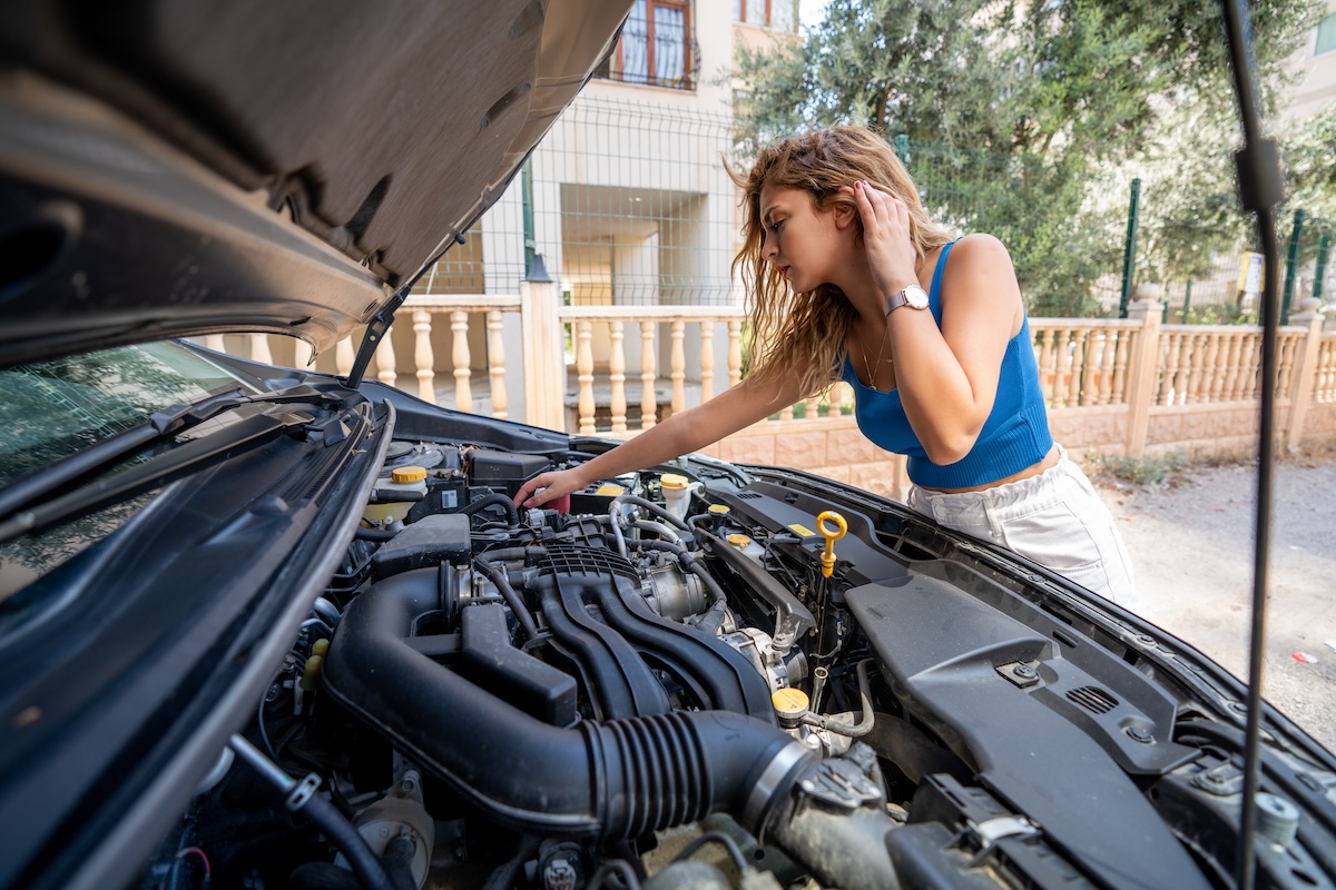 Person looks into open hood of vehicle to troubleshoot problems